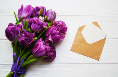 Spring tulip flowers with envelope on a white wooden tableの写真素材