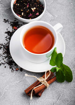 Cup of tea with mint and cinnamon on a gray stone tableの写真素材