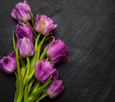 Spring tulip flowers on a black stone tableの写真素材