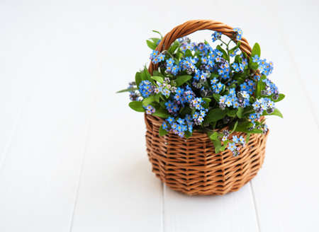 Forget-me-not flowers in  basket on old tableの写真素材