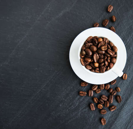 Cup of coffee full of coffee beans on a black background