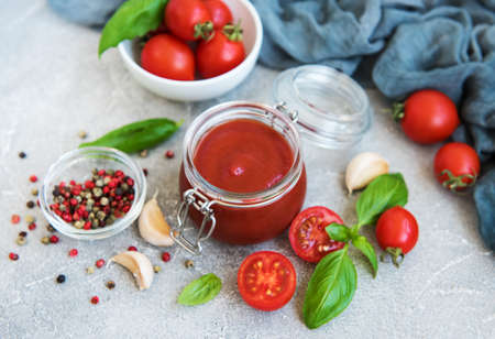 Jar with tomato sauce and ingredients on a stone backgroundの写真素材