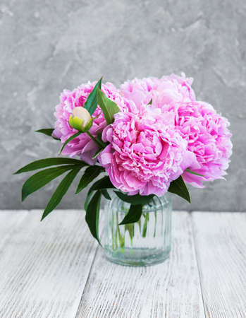 Vase with pink peony flowers on a white wooden table