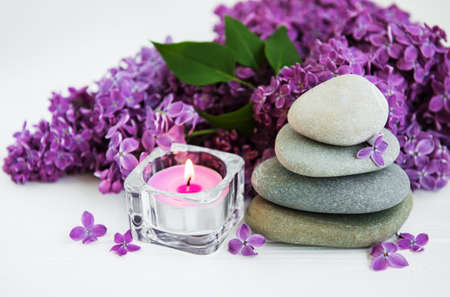 spa products, massage stones, candle and lilac flowersの写真素材