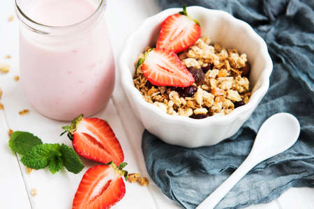Homemade granola with strawberries on a white wooden tableの写真素材