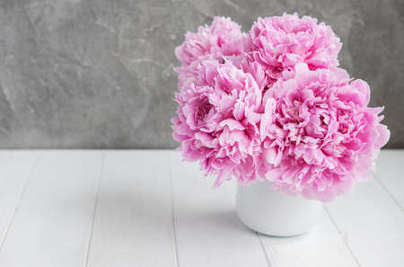 Vase with pink peony flowers on a white wooden tableの写真素材