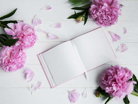 note book with peonies on a white wooden backgroundの写真素材