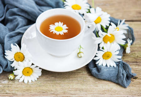 Cup of herbal tea with chamomile flowers on a old wooden tableの写真素材