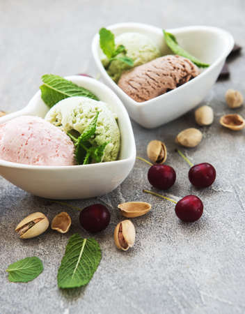 set of ice cream scoops of different colors and flavours with cherries, chocolate and pistachiosの写真素材