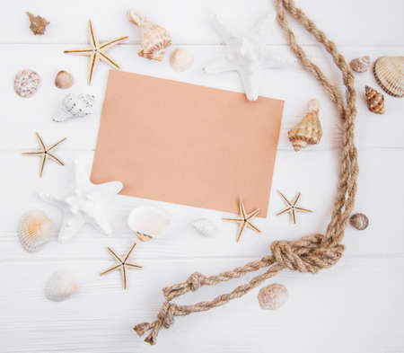 Holiday beach concept with shells, seastars and a blank postcard on a white wooden backgroundの写真素材