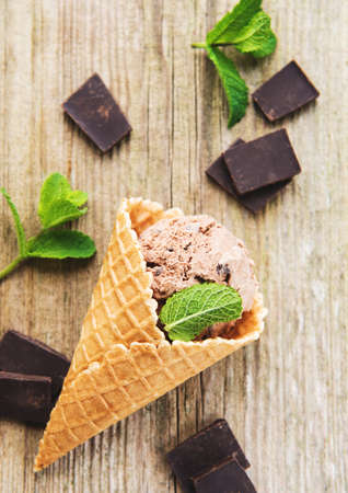 Cone with chocolate ice cream on a old wooden background