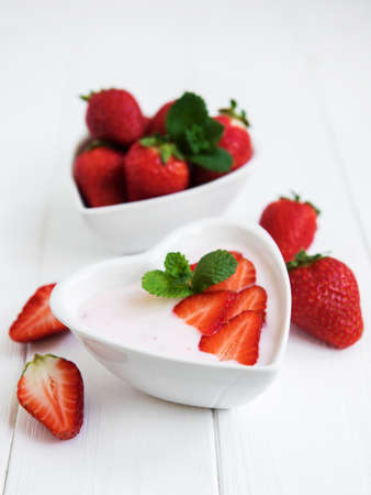 Bowl  with strawberry yogurt on a white wooden tableの写真素材
