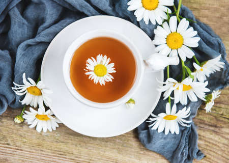 Cup of herbal tea with chamomile flowers on a old wooden tableの写真素材