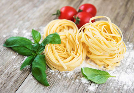 Italian pasta Tagliatelle with green basil on a white wooden tableの写真素材