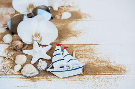 Shells with sand, orchids and sunglasses on a white wooden backgroundの写真素材