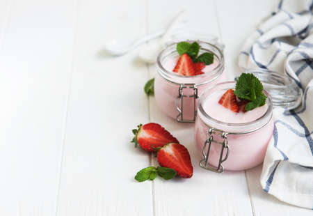 Jars with strawberry yogurt on a white wooden tableの写真素材