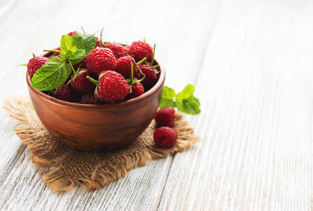 Bowl with fresh raspberries on a old white wooden background