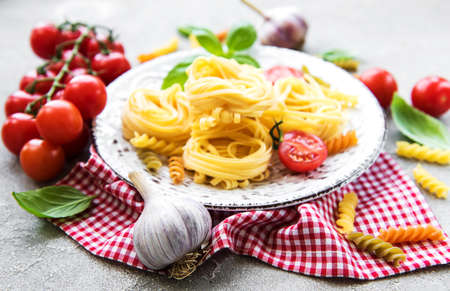 Italian food ingredients, green basil, spices, pasta and tomatoes on a stone backgroundの写真素材