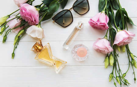 perfume bottles with flowers on a white wooden tableの写真素材