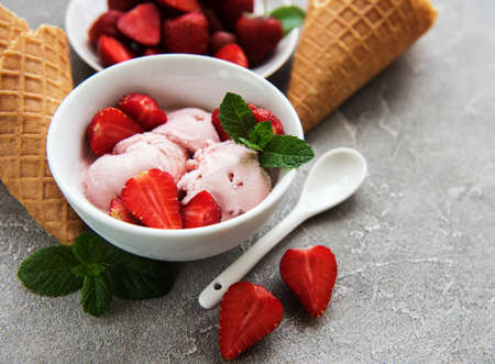 Strawberry ice cream and waffle cone on a stone background