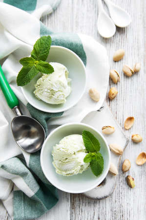 Pistachio ice cream and mint with pistachio nuts on a old wooden background