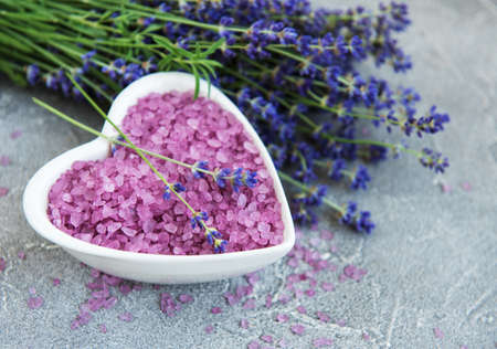 Heart-shaped bowl with sea salt  and fresh lavender flowers on a concrete backgroundの写真素材