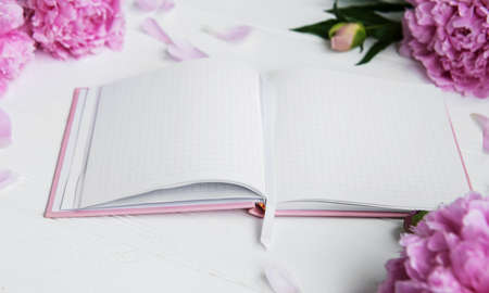 note book with peonies on a white wooden background