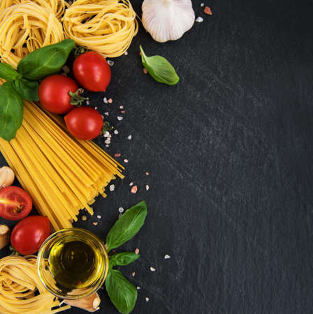 Italian food ingredients. Pasta, tomatoes, basil and spices on a black backgroundの写真素材