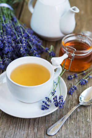 Cup of tea and honey with lavender flowers on a old wooden tableの写真素材