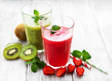 Kiwi and strawberry smoothies with fresh fruits on a old wooden tableの写真素材