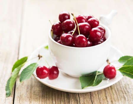 Cup with cherries on a old wooden table