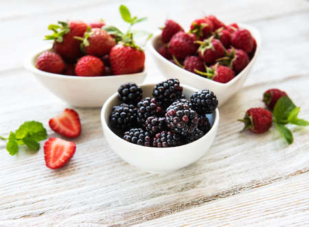 Bowls with summer berries on a old wooden table