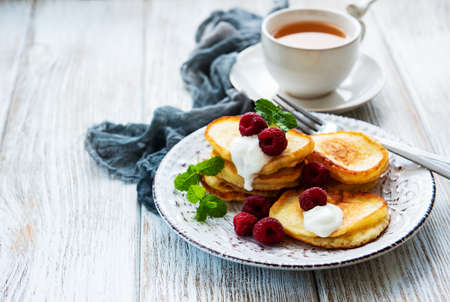 Delicious pancakes with raspberries on white wooden background