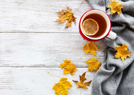 autumn flatlay on wooden backdrop with a cup of tea and fallen dry yellow leaves