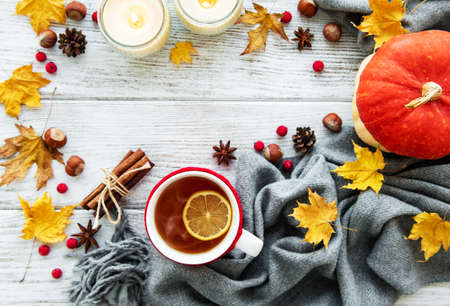 autumn flatlay on wooden backdrop with a cup of tea and fallen dry yellow leavesの写真素材
