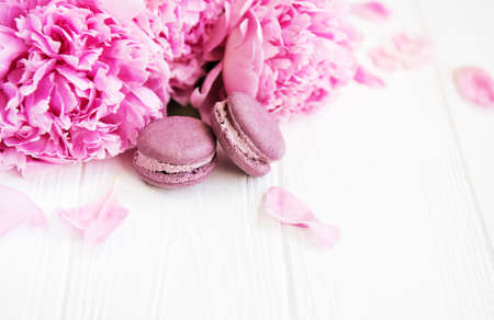 Pink peony flowers with macarons on a white wooden tableの写真素材