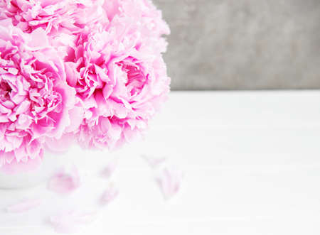 Vase with pink peony flowers on a white wooden tableの写真素材