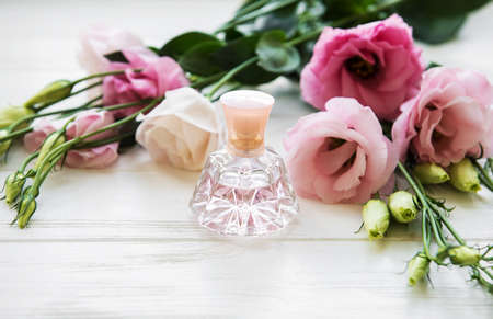 perfume bottles with flowers on a white wooden tableの写真素材