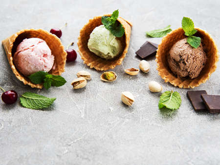 set of ice cream scoops of different colors and flavours with cherries, chocolate and pistachios