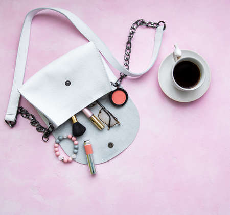White leather bag with cosmetics on a pink  concrete  backgroundの写真素材