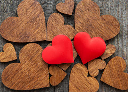 Two Red silk  hearts on a wooden heart backgroundの写真素材