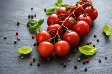 Cherry tomatoes and green basil on a black backgroundの写真素材