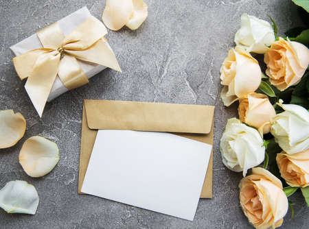 White roses and greeting card on a concrete background