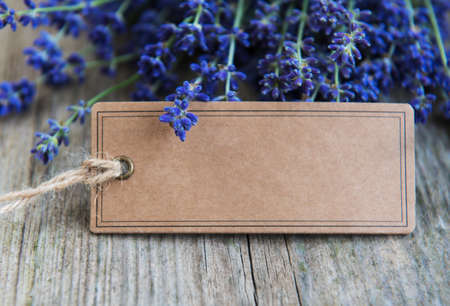 Empty tag and lavender flowers on a old wooden tableの写真素材