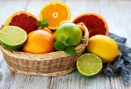Basket with citrus fresh fruits on the white wooden tableの写真素材