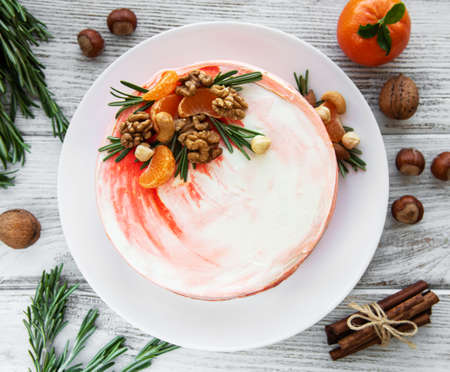 carrot cake decorated with tangerines, nuts and rosemary