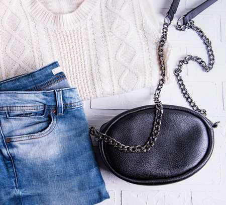 Black leather bag and womens clothing, jeans and sweater