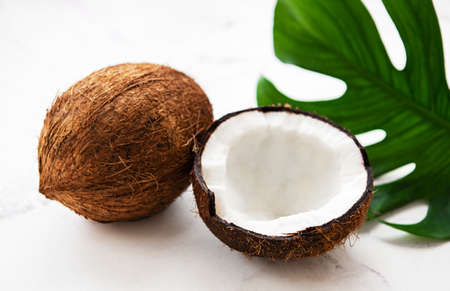 Coconuts with green leaves on a white marble background