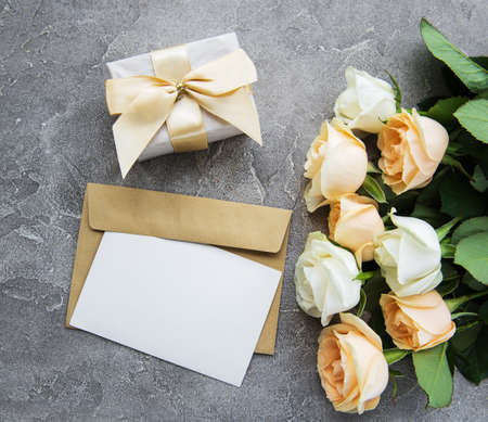 White roses and greeting card on a concrete background