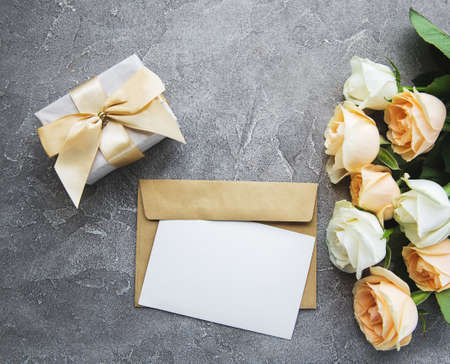 White roses and greeting card on a concrete background